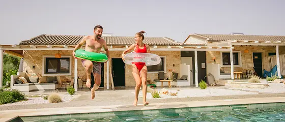 Vader en dochter springen in het zwembad voor een vakantiehuis.