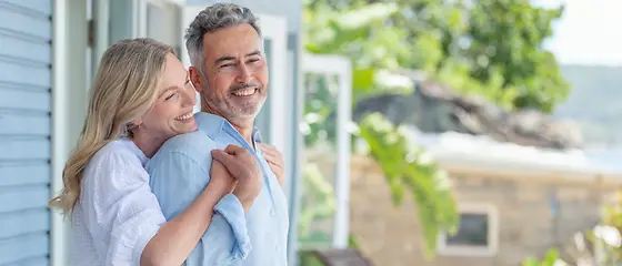 Een paar mensen van middelbare leeftijd worden geconfronteerd met een appartement. Ze omarmt het van achteren.